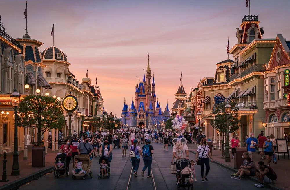 Guests walking along Main Street toward Cinderella Castle at dusk